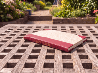 Leather bound condolence book resting on wooden table outdoors.